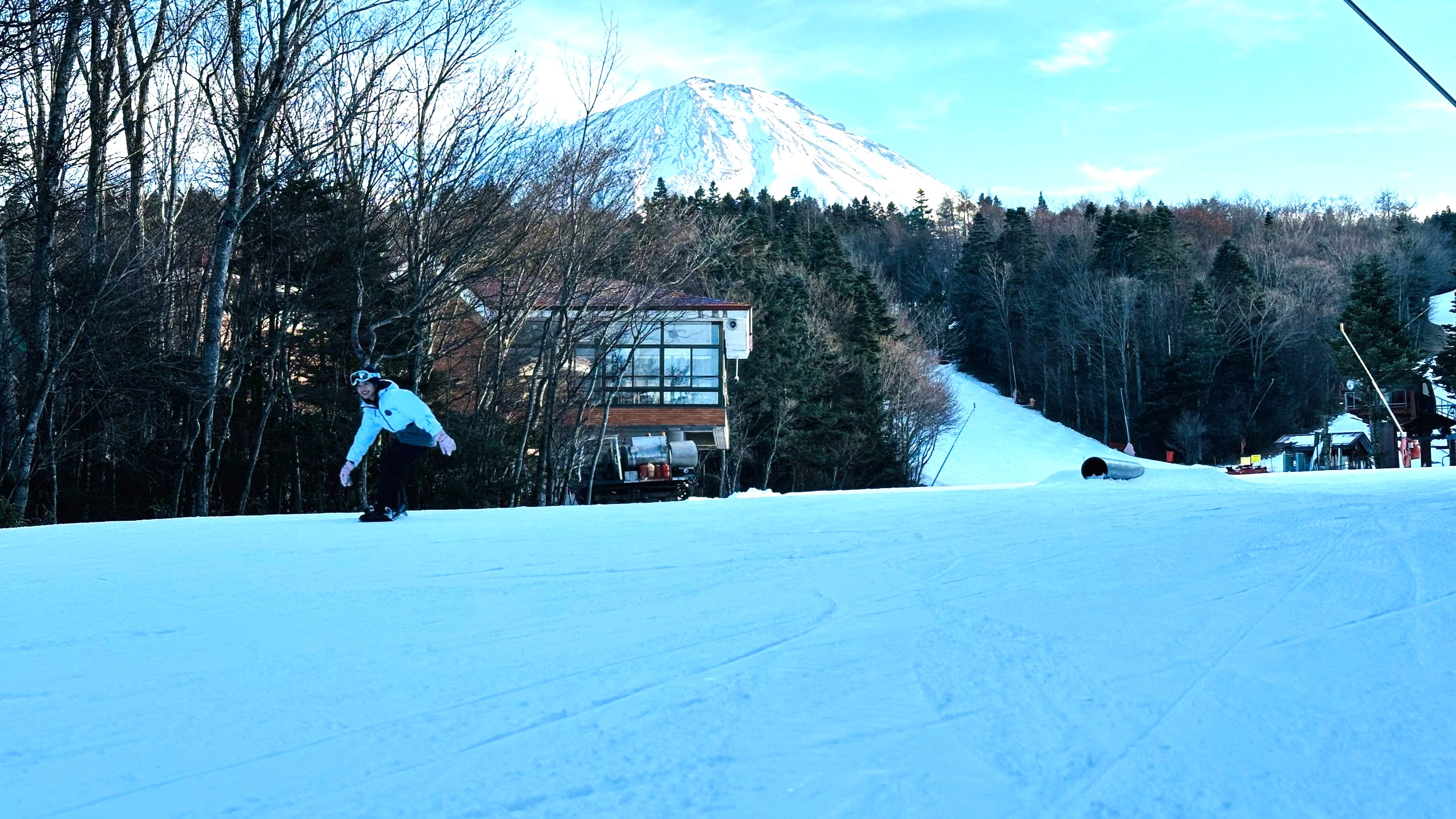 A snowboarder on a slope at Fujiten Snow Resort with Mt. Fuji directly ahead